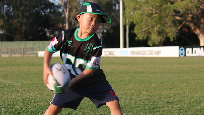 A young boy passing a rugby ball