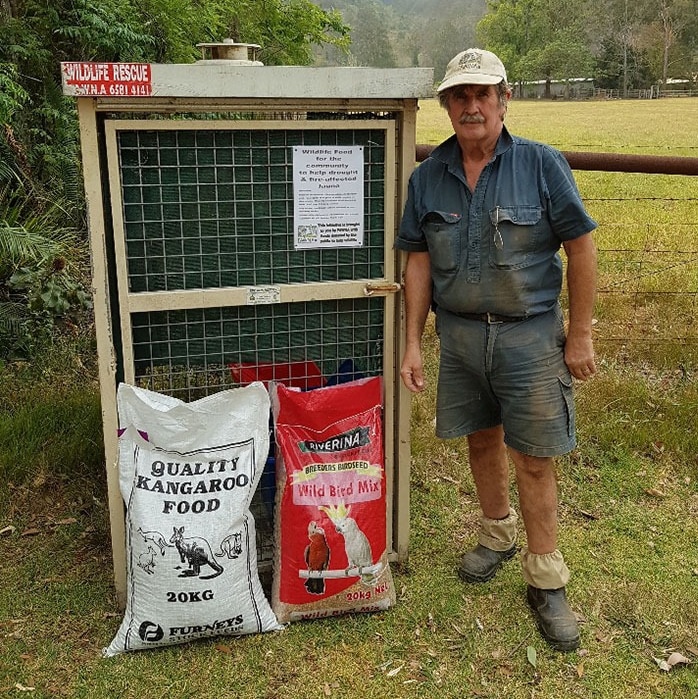 A man standing with bags of kangaroo pellets and wild bird seed