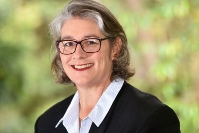 Headshot of lady with glasses smiling towards camera 