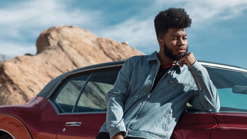 Image of Khalid leaning against a red car