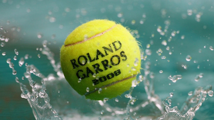 A tennis ball at the French Open bounces in a puddle