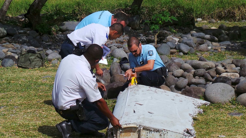 French police inspecting a large piece of plane debris on Reunion Island