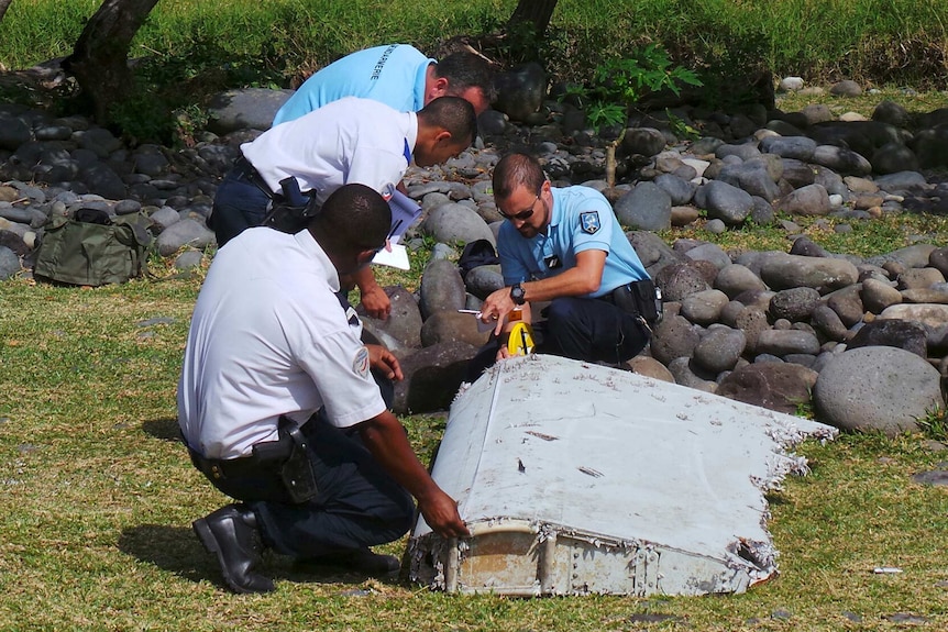 French police inspecting a large piece of plane debris on Reunion Island