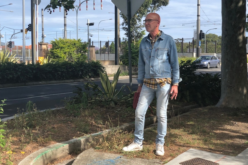 A man standing outside beside a street.