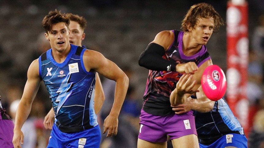 Nat Fyfe looks to handpass during an AFLX exhibition game as an opponent looks on behind him