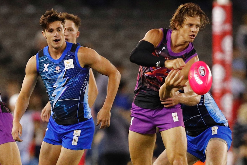 Nat Fyfe looks to handpass during an AFLX exhibition game as an opponent looks on behind him