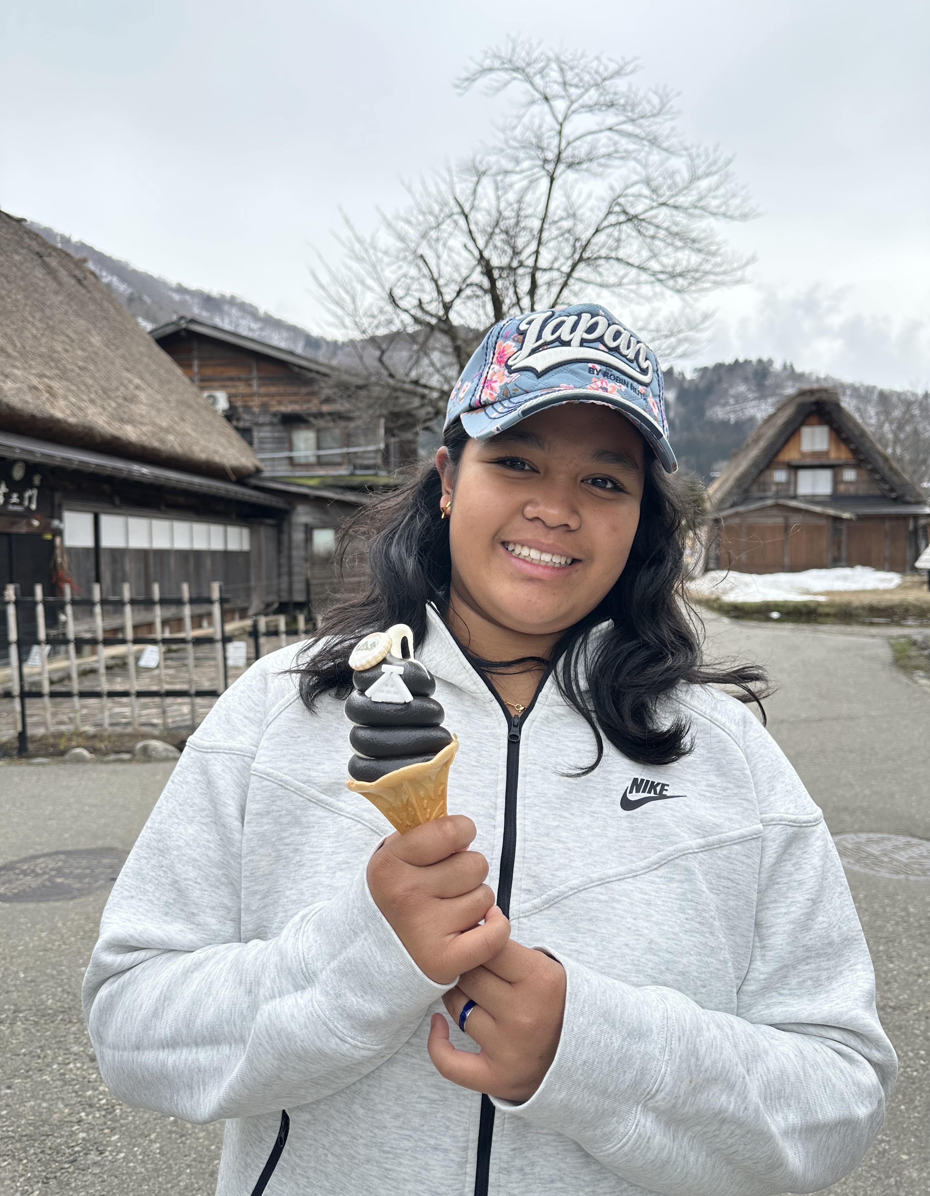 Margo Villa wearing a white jacket and a cap, holding an ice-cream in a cone.