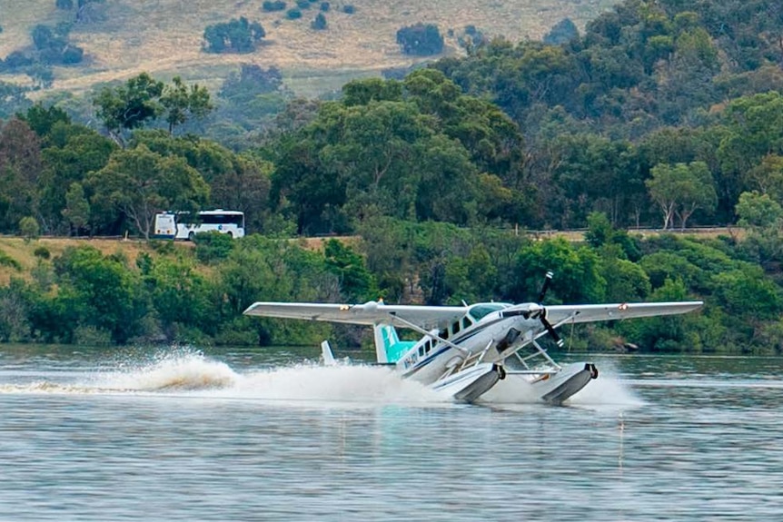A seaplane is touching down in a lake with foam spraying out in its wake.
