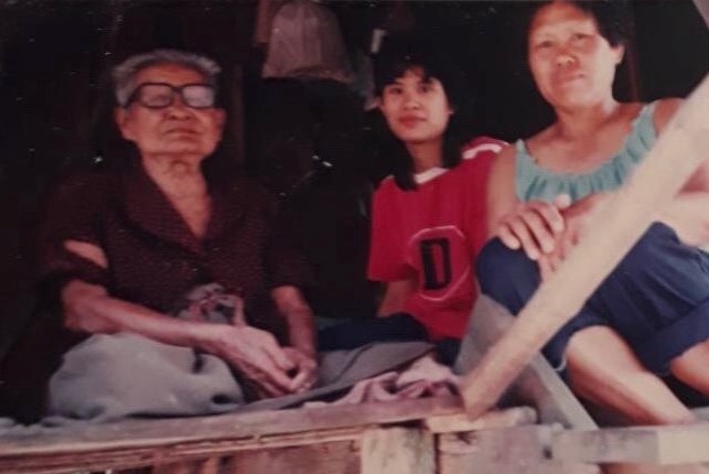 An ages family photograph of old woman, girl and mother sitting on a mat.