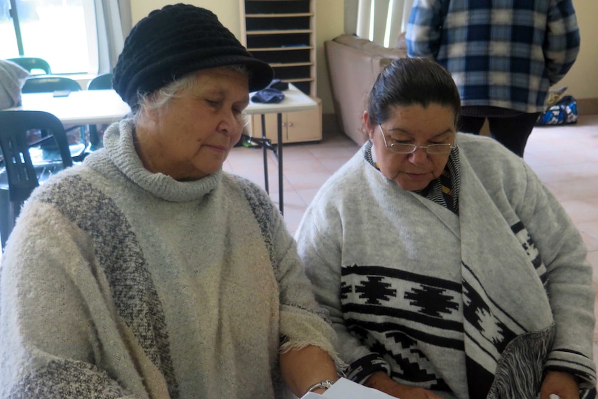 Two women sit in chairs reading a script.