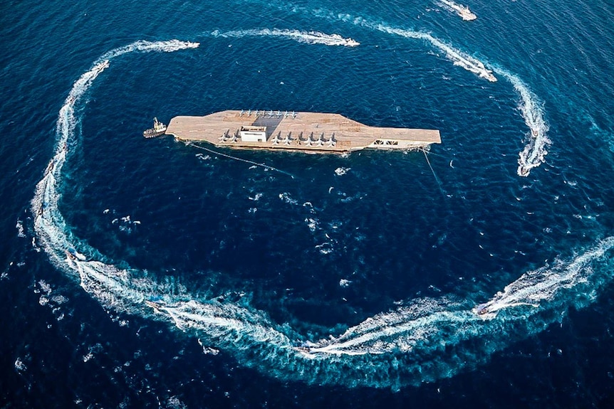 Boats circle an aircraft carrier