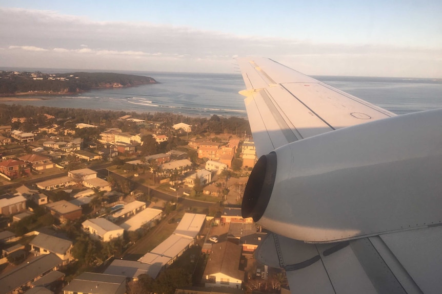 On board a flight looking out the window over a coastal town