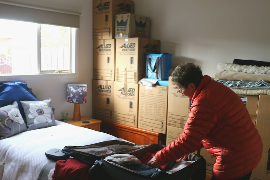 Jan Smith packs a suitcase surrounded by packing boxes.