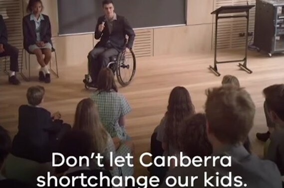 A student in a wheelchair makes a speech in a classroom.