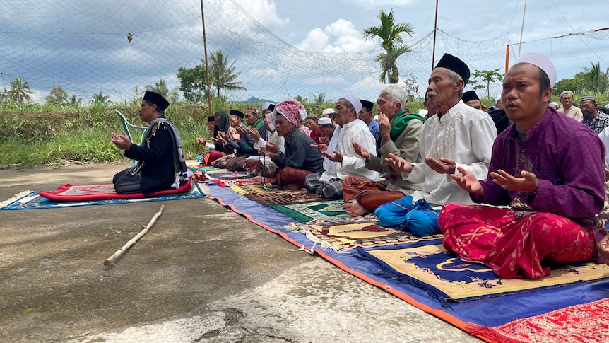 Indonesians pray outdoors after a deadly earthquake devastates the city