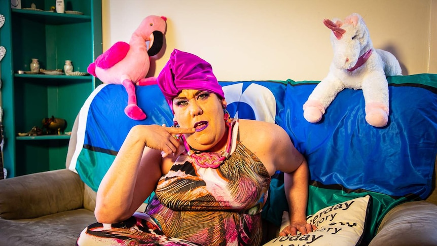 Shawn Cady dressed as their drag identity MadB, posing in front of the Torres Strait Islander flag ahead of Miss First Nations.