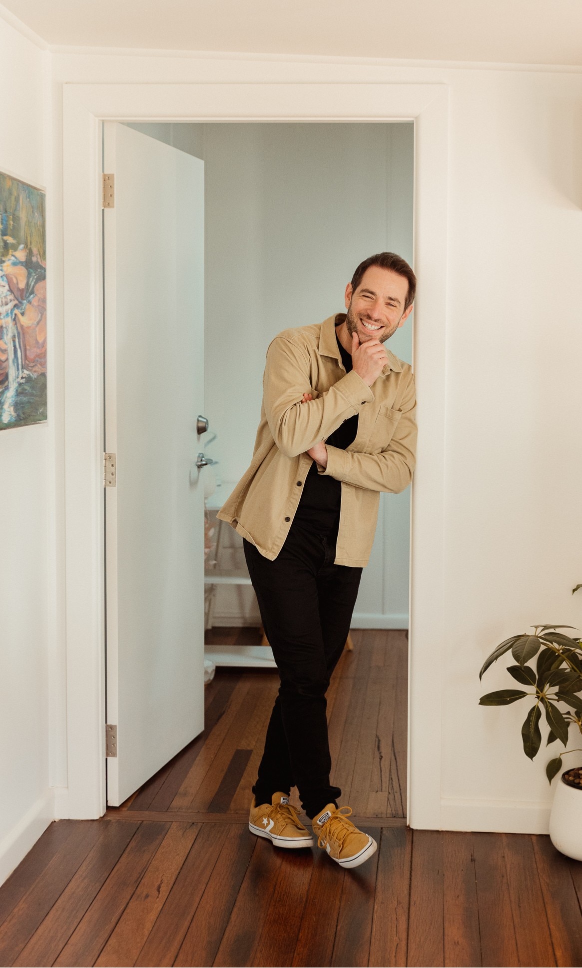 A smiling man in casual clothes stands in the doorway of an office.