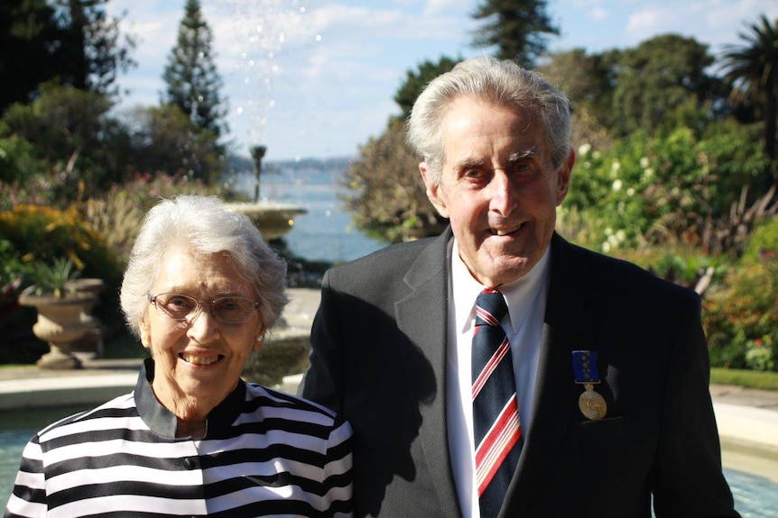 An older couple smile for a mid shot.