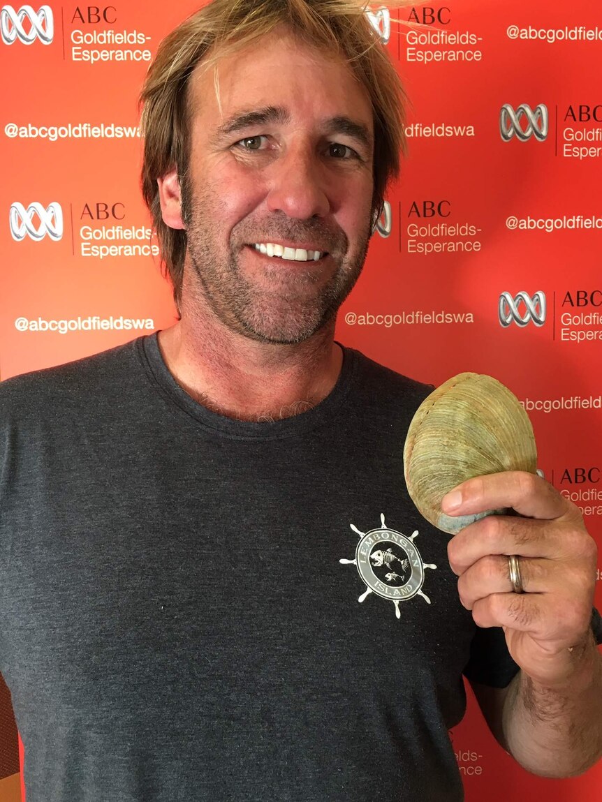 Close up photo of man holding abalone shell in ABC studio