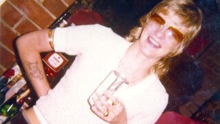 Shirley Finn's former girlfriend Rose Black stands smiling holding a drink in a glass and wearing sunglassses.