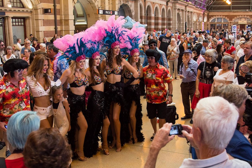 Showgirls and Elvis impersonators pose for photographs at Sydney Central railway station.