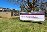 A sign that reads 'Broome Regional Prison' in front of a large metal gate and fence.