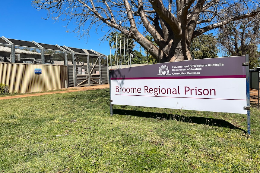 A sign that reads 'Broome Regional Prison' in front of a large metal gate and fence.