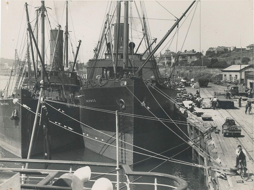 A monochrome image of a busy wharf scene in 1940s  Devonport, two steel ships being unloaded.