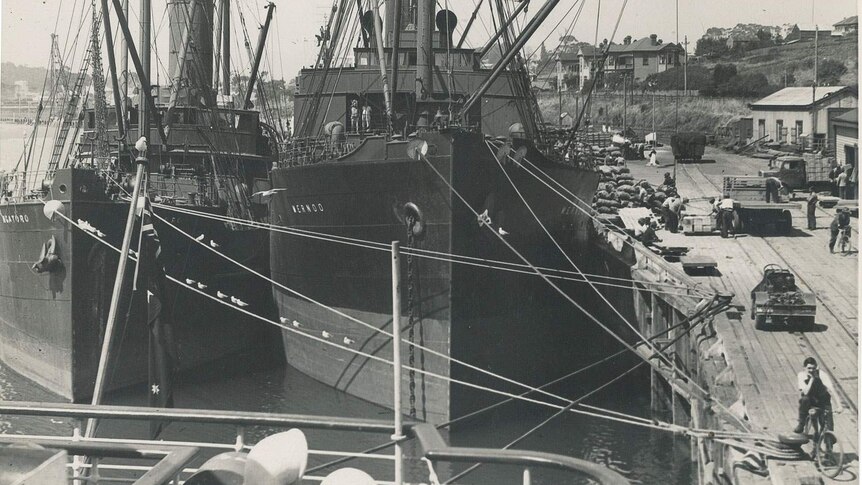 A monochrome image of a busy wharf scene in 1940s  Devonport, two steel ships being unloaded.