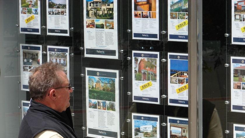 Man looking at real estate ads in a shop window