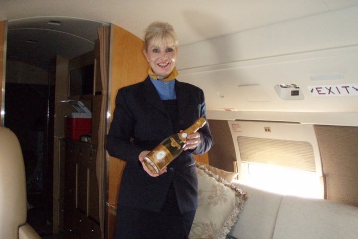Woman holds an expensive bottle of champagne on board a private jet.