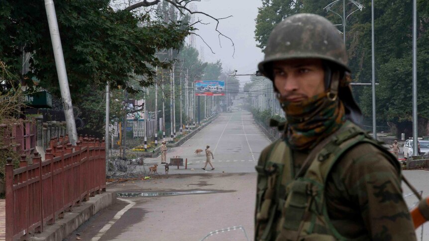 An Indian paramilitary soldier stands guard on a deserted road leading towards an Indian Independence Day parade in Kashmir.