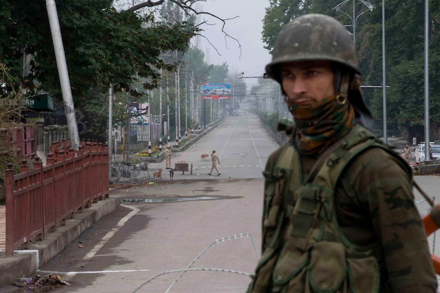 An Indian paramilitary soldier stands guard on a deserted road leading towards an Indian Independence Day parade in Kashmir.