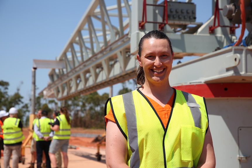 Une femme avec une queue de cheval brune portant des sourires haute visibilité sur un chantier