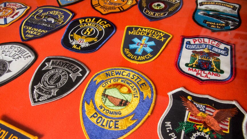 Embroidered patches sit on a red felt board.