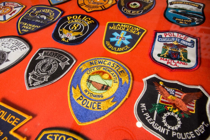 Embroidered patches sit on a red felt board.