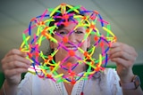 A middle aged woman holding a colourful see through plastic toy in front of her face 