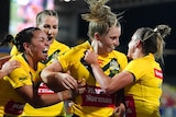 Jillaroos players rush to embrace Tarryn Aiken after she scored a try at the Rugby League World Cup against New Zealand.