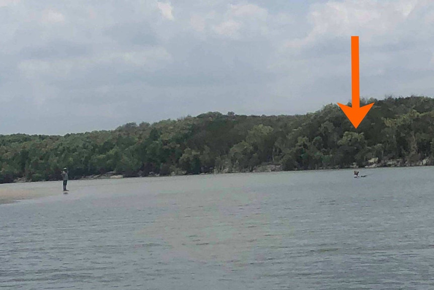 A man fishing chest-deep in crocodile-infested water