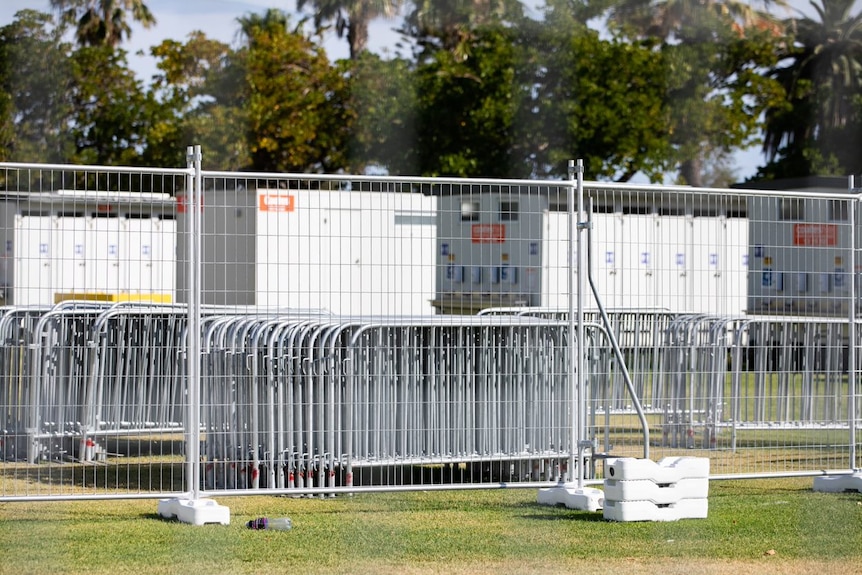 A wide shot of steel fencing stacked with portaloos in the background.