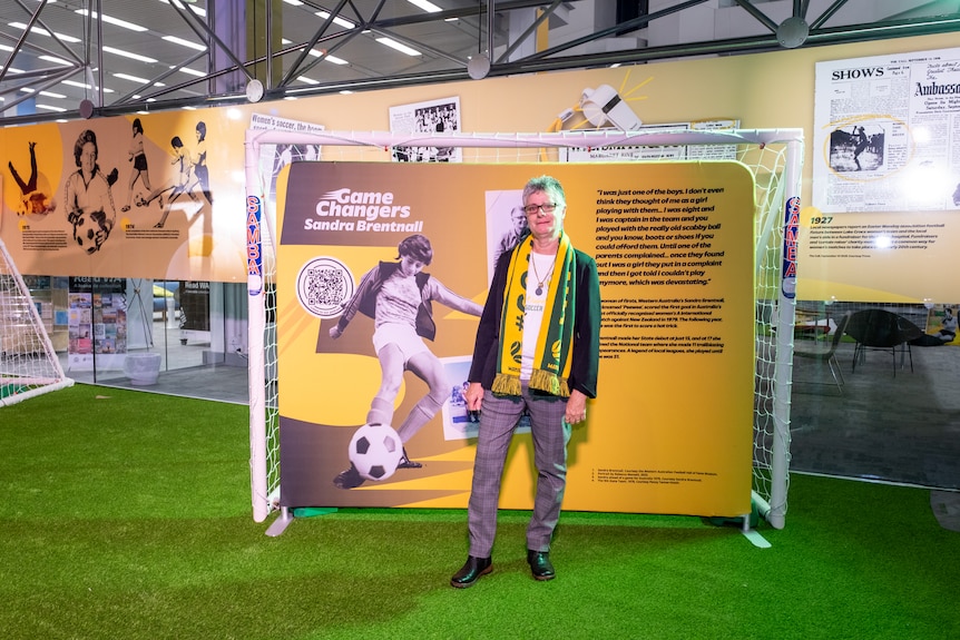 Sandra Brentnall stands in front of an old photo of herself