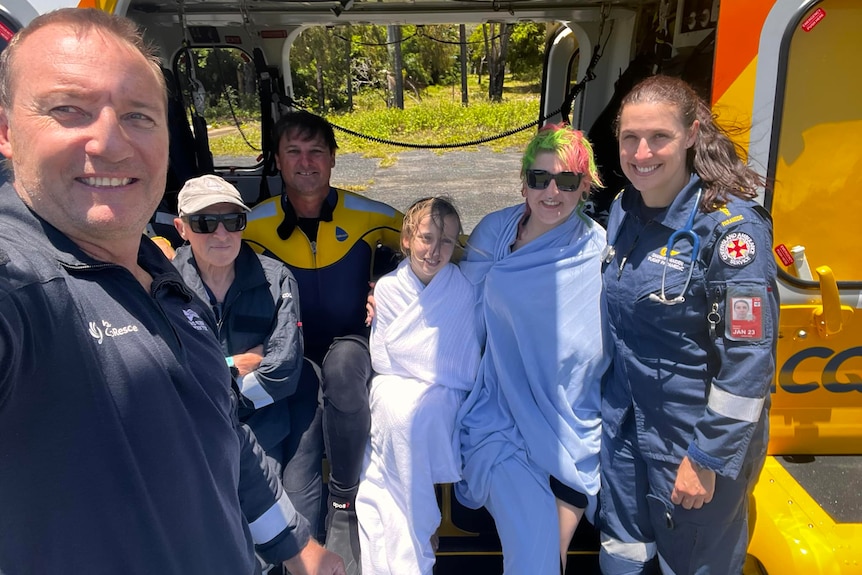 A bunch of people sitting inside a helicopter after being rescued at sea with those who rescued them.