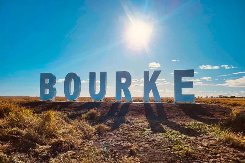 A sign spelling Bourke stands among the landscape