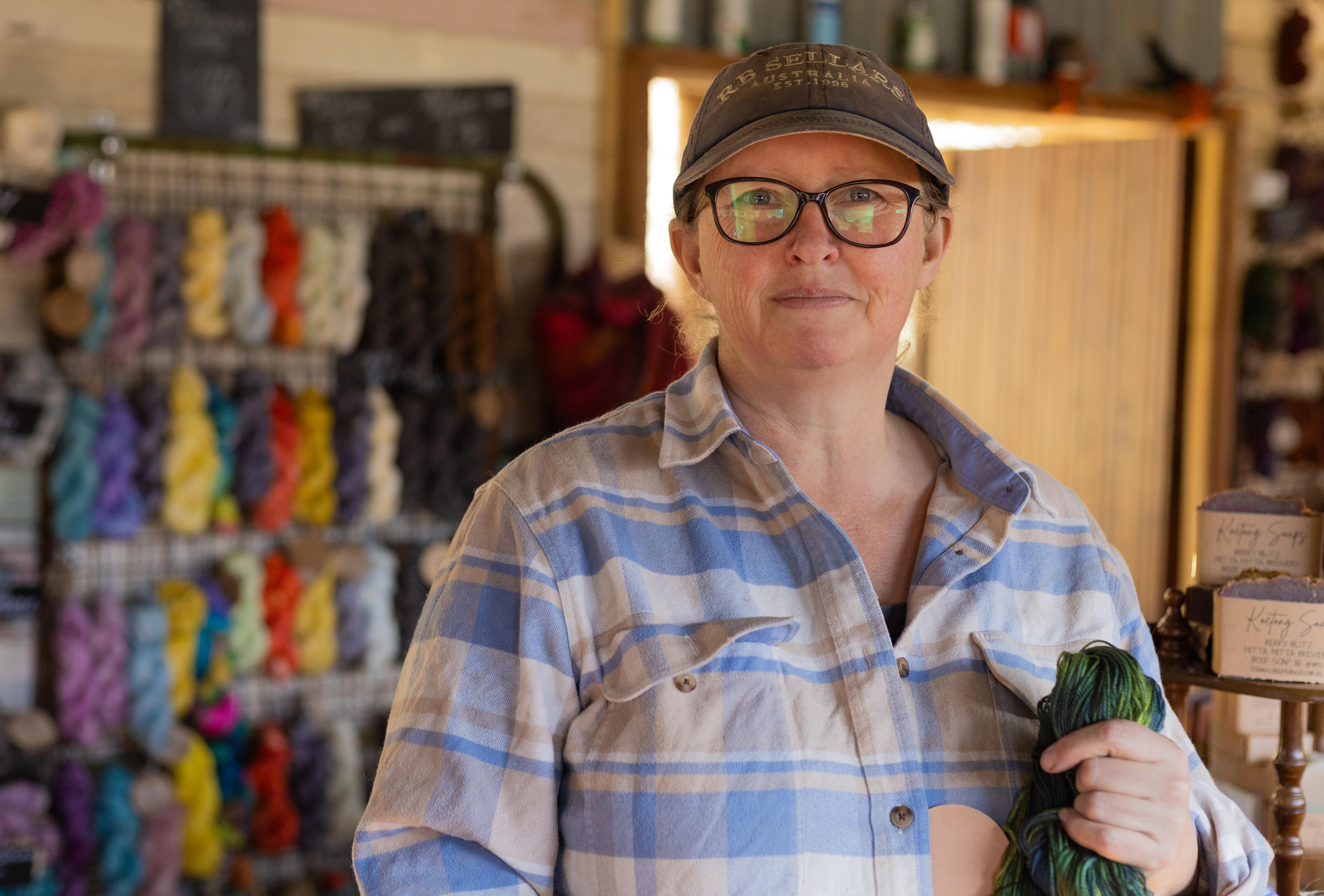A woman stands in a room with wool displayed on the walls