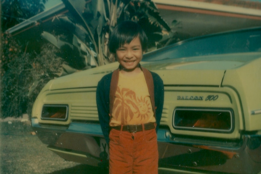 A small child standing in front of a car
