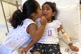 Tharnicaa comforted by sister Kopica in hospital on Christmas Island