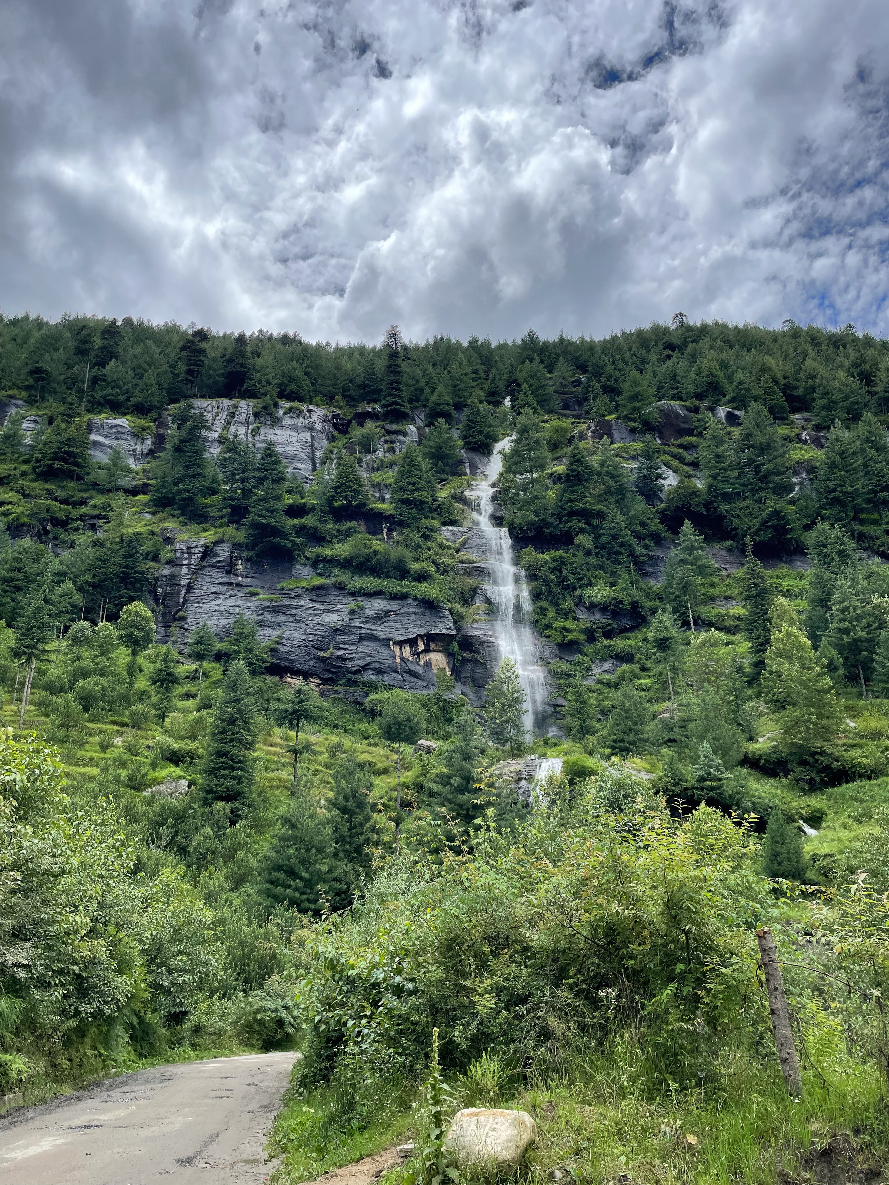 A lush green mountainside with a waterfall running through the middle.
