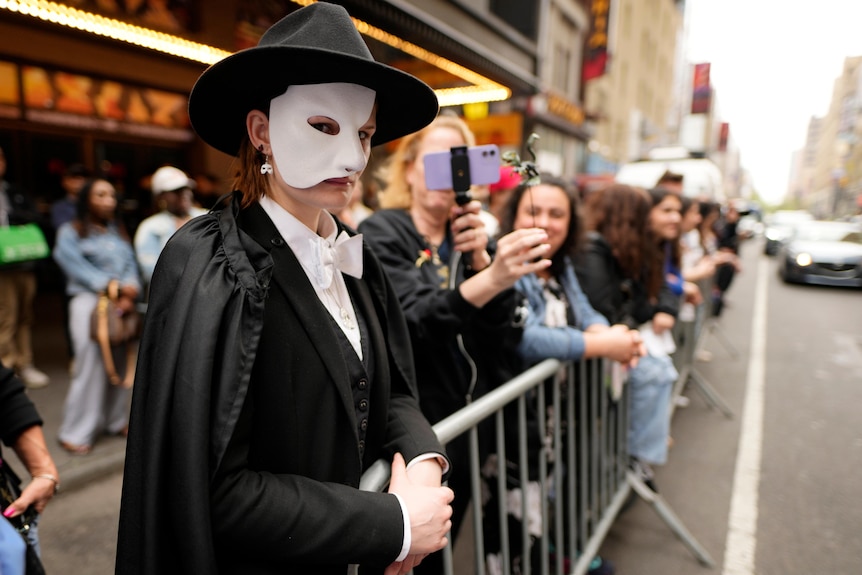 A person dressed as the phantom of the operate in a queue on the street