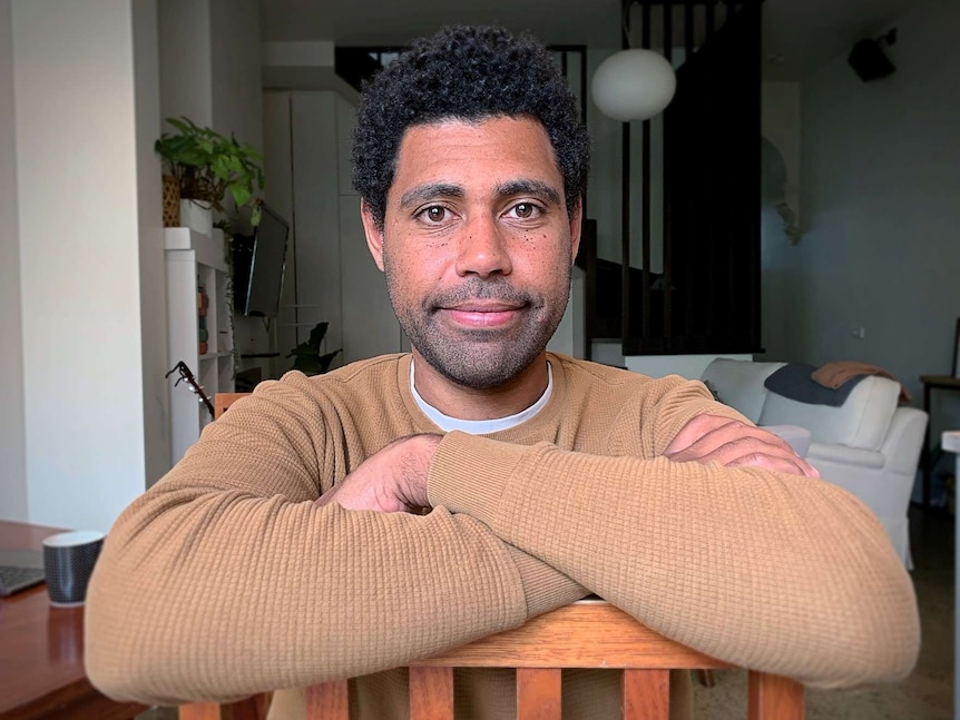 Jesse Kemelfield sits on a seat with his arms folded over the back rest.