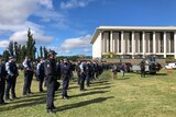 A row of police line up on the lawn outside the national library of australia
